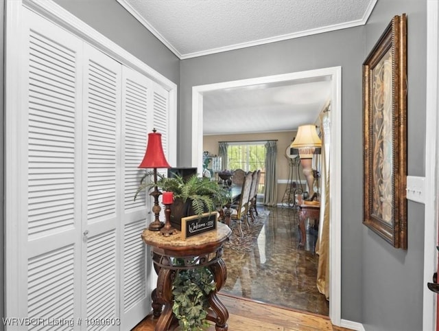 corridor featuring a textured ceiling, wood finished floors, ornamental molding, and baseboards