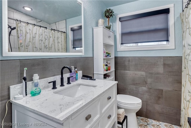 bathroom with curtained shower, toilet, tile walls, and vanity