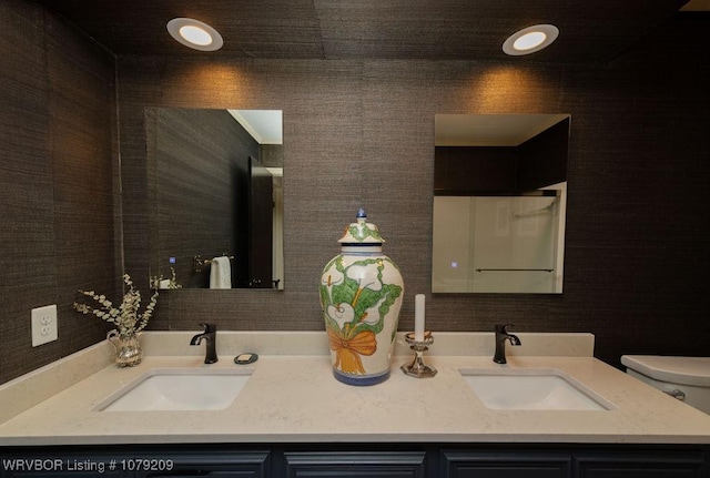 bathroom featuring double vanity, toilet, and a sink