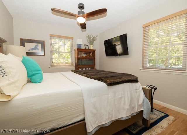 bedroom featuring multiple windows, ceiling fan, baseboards, and wood finished floors