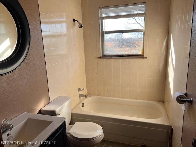 full bathroom featuring vanity, tiled shower / bath combo, and toilet