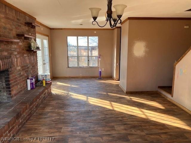 unfurnished living room featuring a fireplace, dark hardwood / wood-style flooring, an inviting chandelier, and ornamental molding