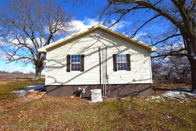 view of property exterior with central AC and a lawn