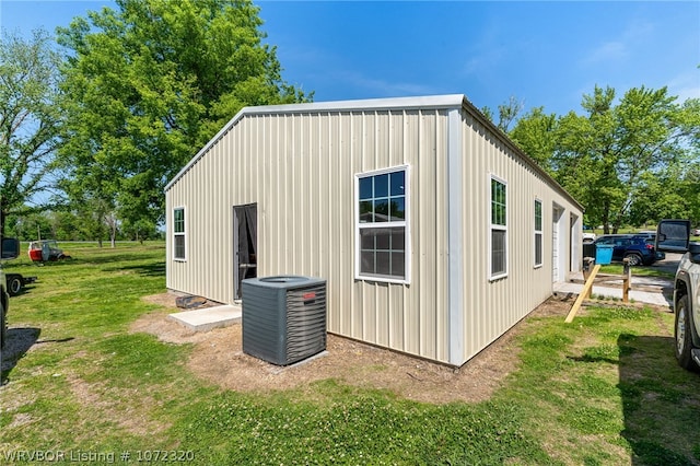 view of outdoor structure featuring central AC unit and a yard