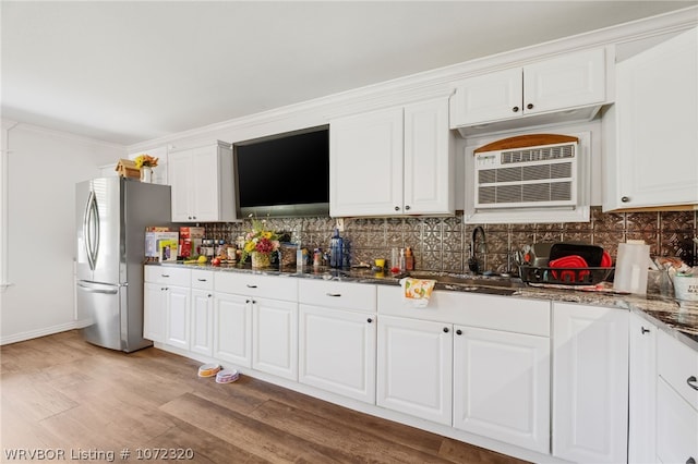 kitchen featuring dark stone counters, sink, light hardwood / wood-style flooring, white cabinetry, and stainless steel refrigerator