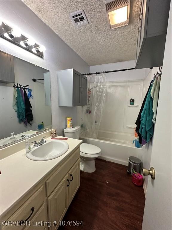 full bathroom with a textured ceiling, toilet, shower / tub combo with curtain, vanity, and hardwood / wood-style flooring