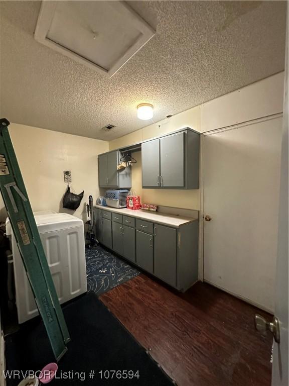 kitchen featuring a textured ceiling, dark hardwood / wood-style floors, and washer / clothes dryer