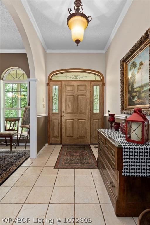 tiled foyer featuring ornamental molding