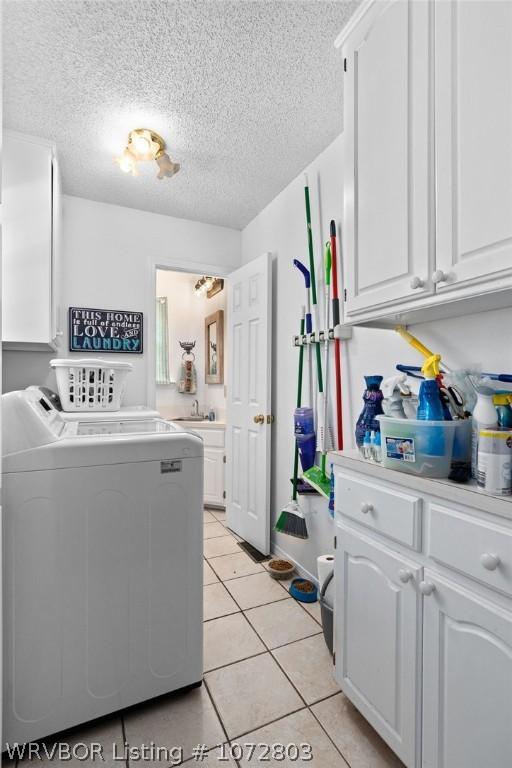 laundry area featuring cabinets, sink, independent washer and dryer, a textured ceiling, and light tile patterned flooring