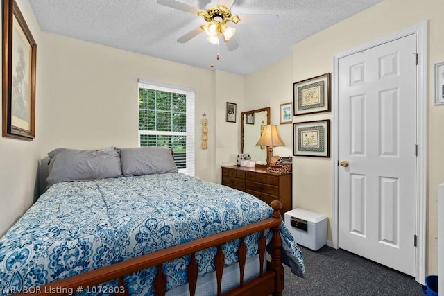 bedroom featuring a textured ceiling, dark carpet, and ceiling fan