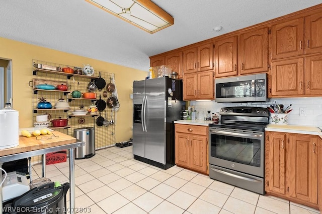 kitchen featuring backsplash, light tile patterned floors, and stainless steel appliances