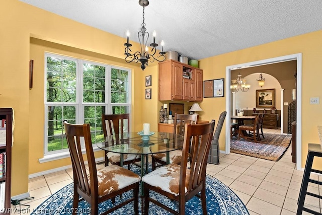 dining space featuring light tile patterned floors, a textured ceiling, and a chandelier