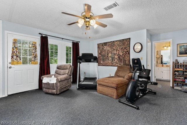 exercise area with ceiling fan and a textured ceiling