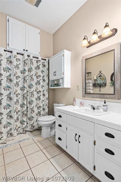 bathroom with tile patterned flooring, vanity, and toilet