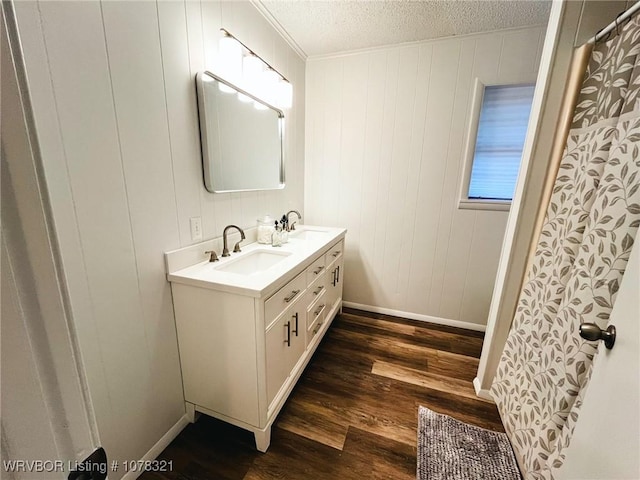 bathroom featuring a textured ceiling, wooden walls, vanity, and hardwood / wood-style flooring