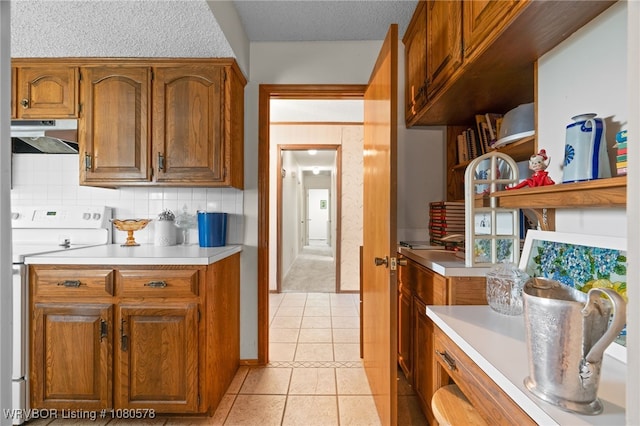 kitchen featuring electric range, under cabinet range hood, light countertops, and brown cabinets