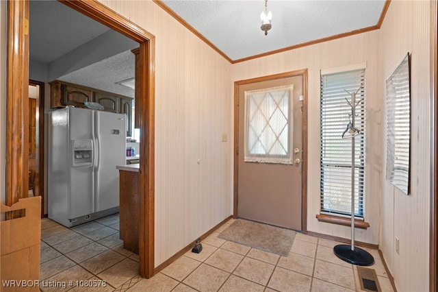 foyer entrance featuring baseboards, light tile patterned floors, a textured ceiling, and crown molding