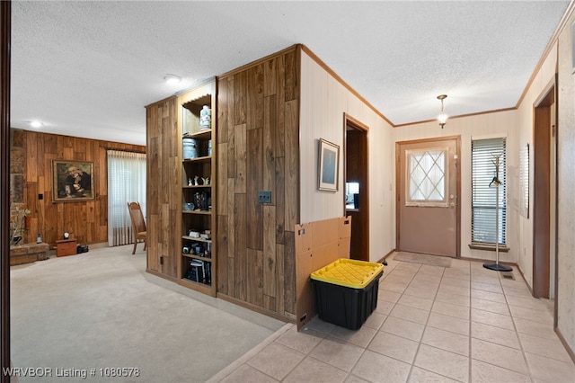 foyer with baseboards, wooden walls, a textured ceiling, and crown molding