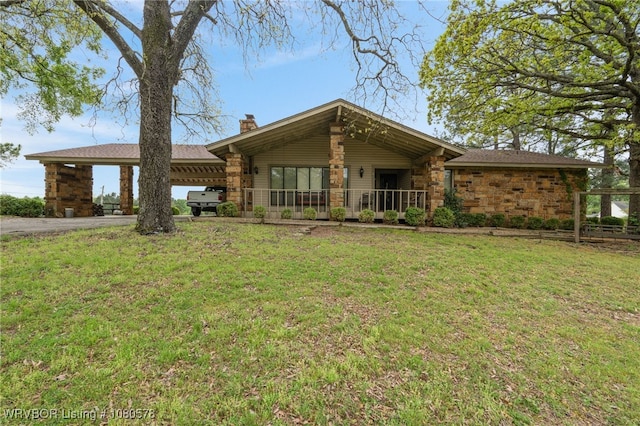 view of front of home with a carport, aphalt driveway, stone siding, a chimney, and a front yard