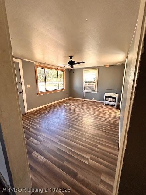 unfurnished room with heating unit, cooling unit, dark wood-type flooring, and ceiling fan