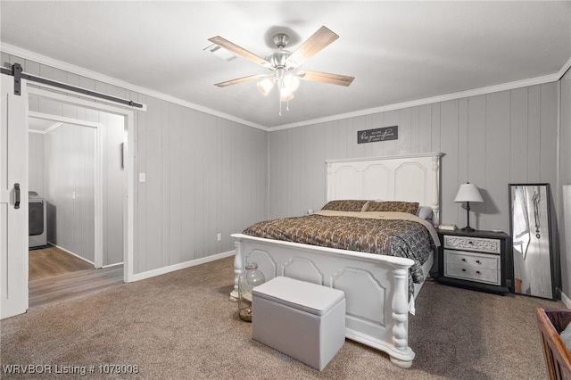 bedroom featuring washer / clothes dryer, carpet flooring, ceiling fan, crown molding, and a barn door