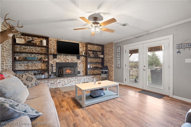 living room with crown molding, ceiling fan, wood-type flooring, a textured ceiling, and french doors