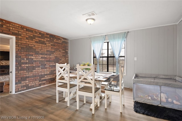 dining space with hardwood / wood-style flooring and brick wall