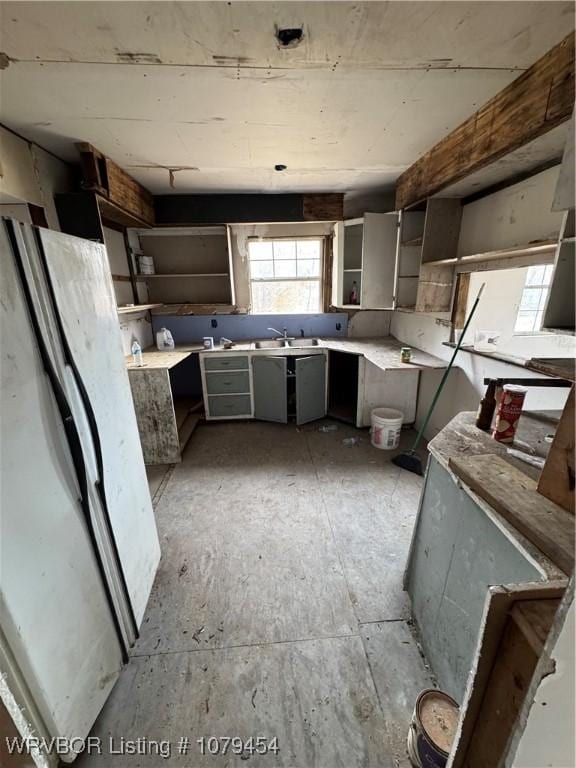 kitchen featuring open shelves, light countertops, gray cabinets, and a sink