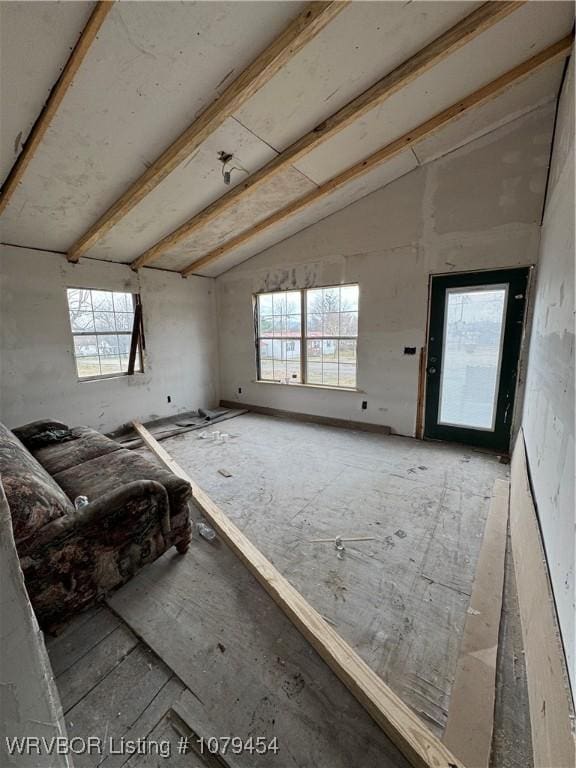 unfurnished living room featuring lofted ceiling with beams