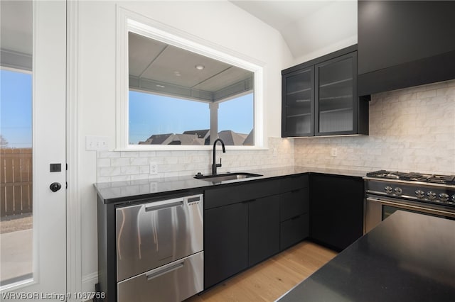 7631 Woodbine Ln, Fort Smith, AR 72916 - kitchen featuring dark cabinets, appliances with stainless steel finishes, light wood-style flooring, decorative backsplash, and glass insert cabinets