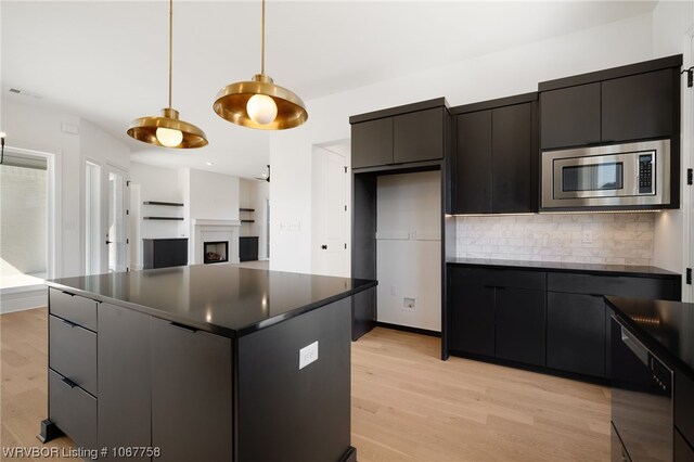 kitchen featuring pendant lighting, backsplash, light wood-type flooring, a kitchen island, and stainless steel appliances