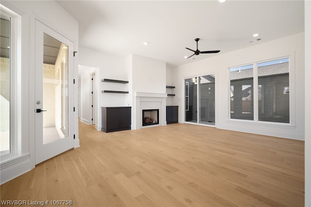 unfurnished living room with light hardwood / wood-style flooring, ceiling fan, and a healthy amount of sunlight