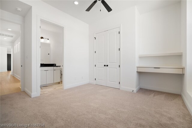 unfurnished bedroom featuring a closet, ceiling fan, ensuite bathroom, and light carpet