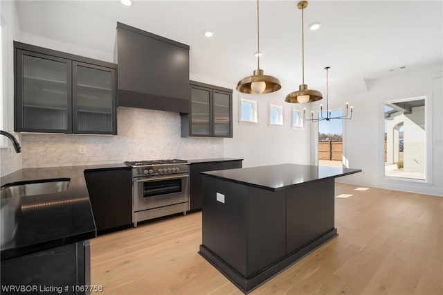 kitchen with sink, a kitchen island, backsplash, decorative light fixtures, and high end range