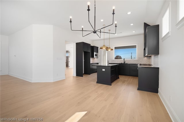 7631 Woodbine Ln, Fort Smith, AR 72916 - kitchen with a center island, dark cabinets, a chandelier, backsplash, and light wood-type flooring