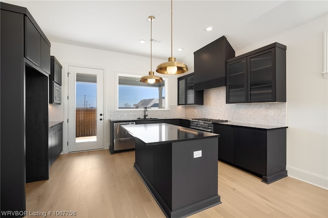 7631 Woodbine Ln, Fort Smith, AR 72916 - kitchen featuring dark cabinetry, a center island, light wood-type flooring, tasteful backsplash, and hanging light fixtures