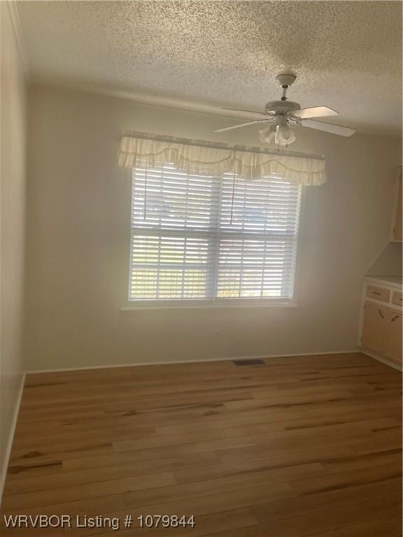 606 Highland Dr, Charleston, AR 72933 - unfurnished dining area with wood finished floors, a textured ceiling, ceiling fan, baseboards, and visible vents