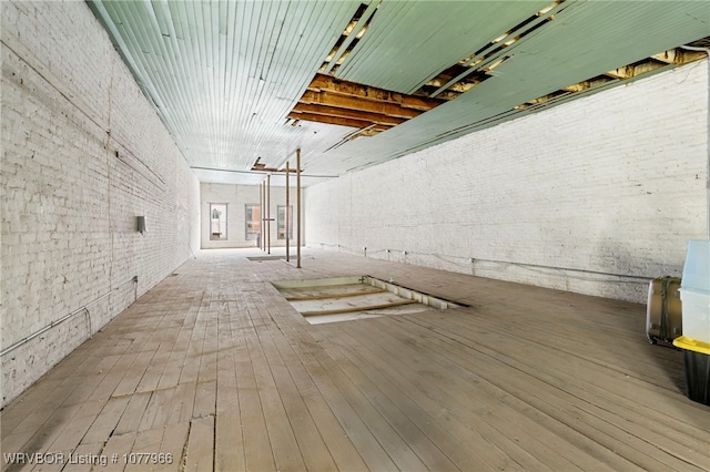 interior space with hardwood / wood-style floors and brick wall