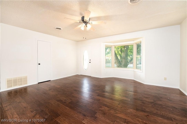 unfurnished room with a textured ceiling, ceiling fan, and dark wood-type flooring