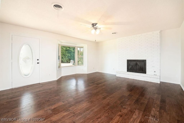 unfurnished living room featuring ceiling fan, dark hardwood / wood-style flooring, and a brick fireplace