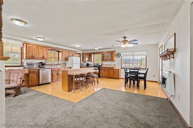 kitchen with ceiling fan, a center island, stainless steel appliances, heating unit, and a breakfast bar