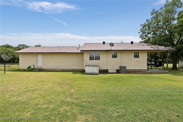 back of property with central AC and a lawn