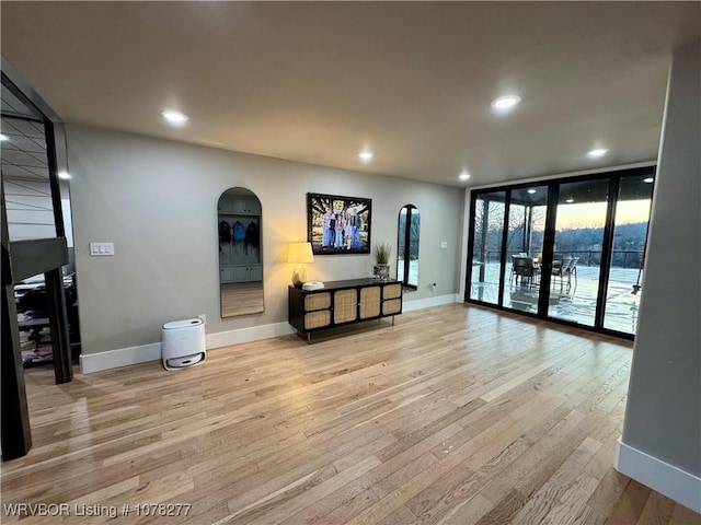 living room with floor to ceiling windows, light hardwood / wood-style floors, and french doors