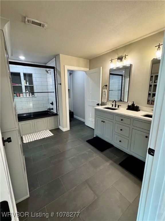 bathroom with vanity, a textured ceiling, and bathing tub / shower combination