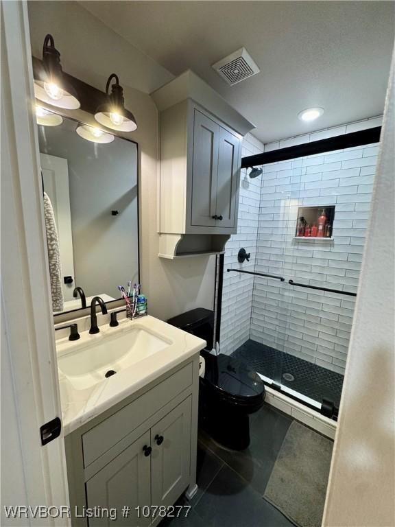 bathroom featuring tile patterned flooring, vanity, toilet, and walk in shower