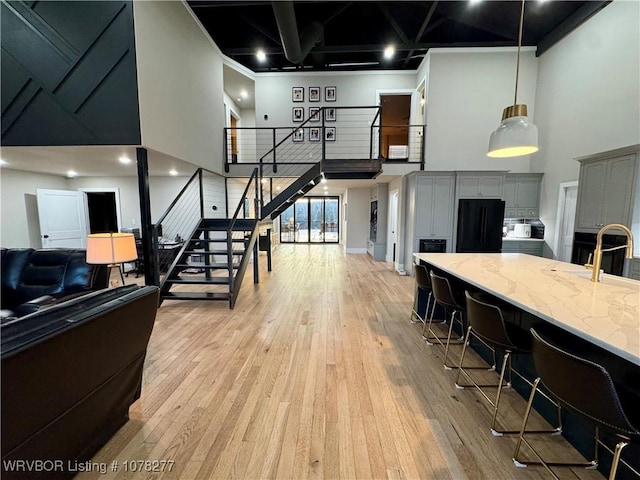 interior space with a kitchen bar, a towering ceiling, light stone counters, pendant lighting, and gray cabinets