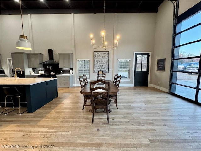 dining space featuring light hardwood / wood-style floors, a high ceiling, and an inviting chandelier