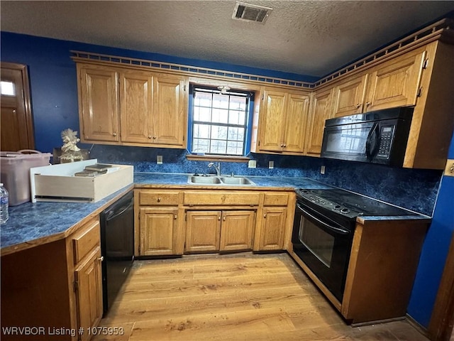 kitchen with sink, black appliances, light hardwood / wood-style floors, and a textured ceiling