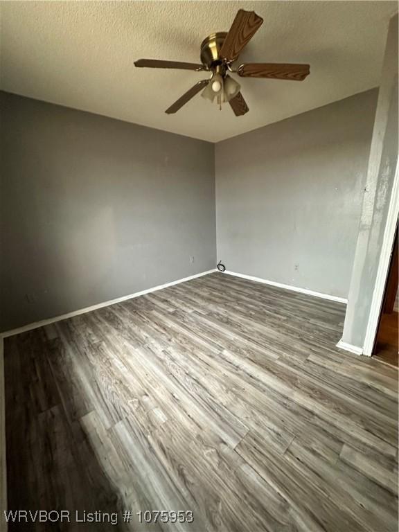 empty room featuring ceiling fan, a textured ceiling, and dark hardwood / wood-style flooring