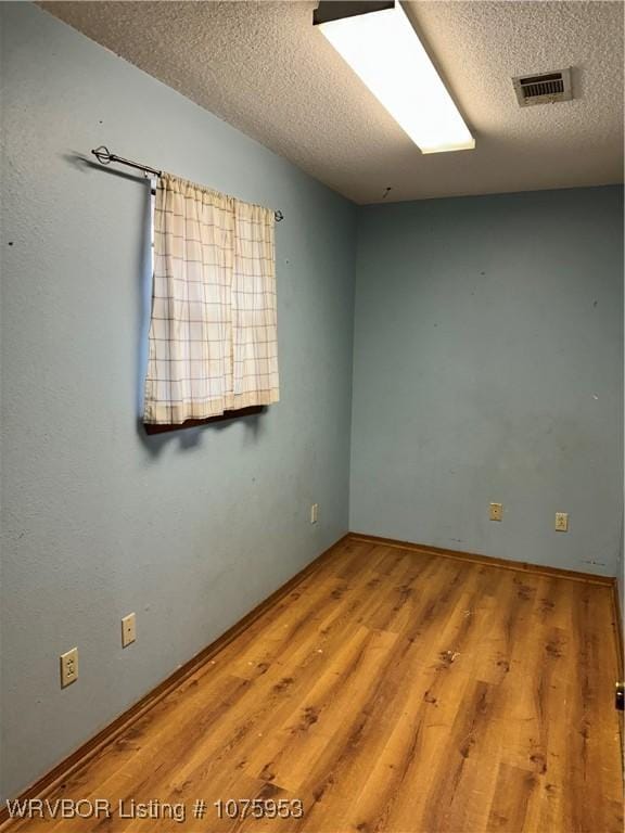 unfurnished room with hardwood / wood-style floors and a textured ceiling